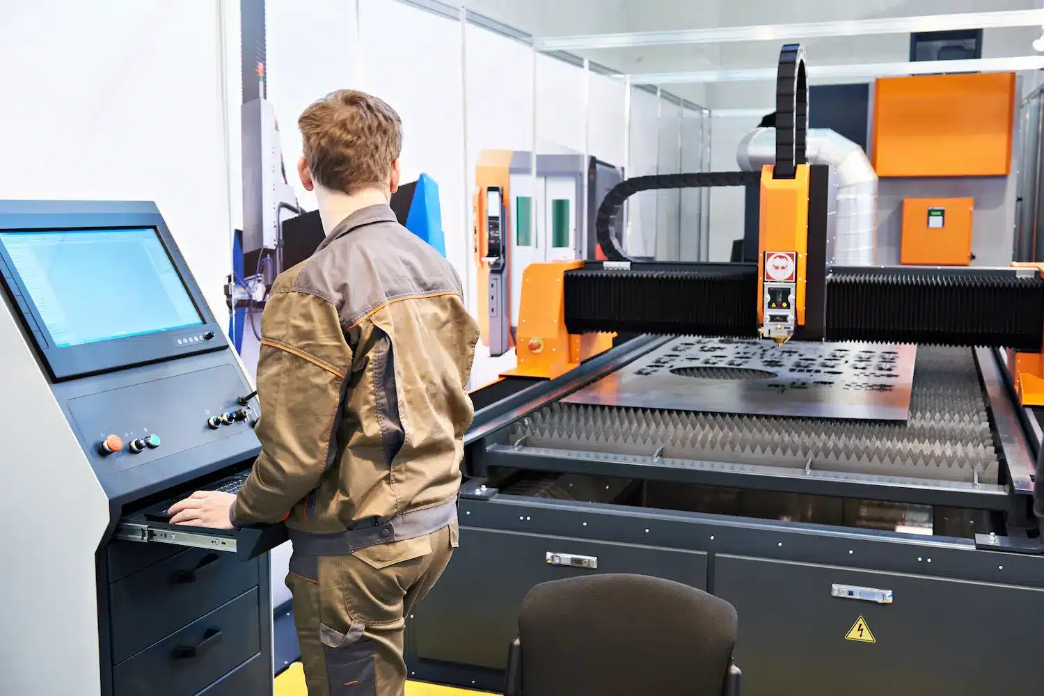 Laserschneiden mit Maschine Ein Arbeiter steht vor einer Laserschneide-Maschine und schneidet individuelle Laserteile