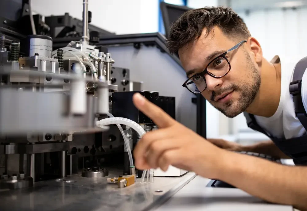 Person baut eine individuelle Maschine zusammen und zeigt auf Bauteil